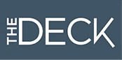 The image shows a logo reading &ldquo;THE DECK&rdquo; in white letters on a blue-gray rectangular background.