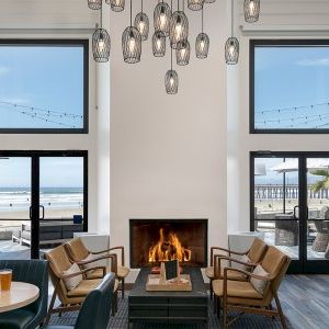 A chic beachside lounge with a cozy fireplace, modern seating, and large glass doors opening to the ocean view.
