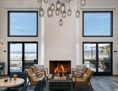A chic beachside lounge with a cozy fireplace, modern seating, and large glass doors opening to the ocean view.